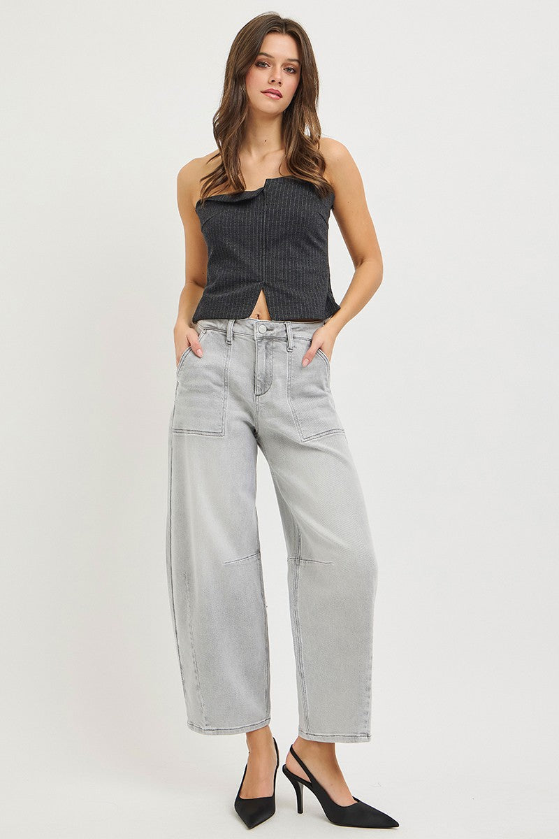 Woman wearing a black top and light gray jeans on a white background