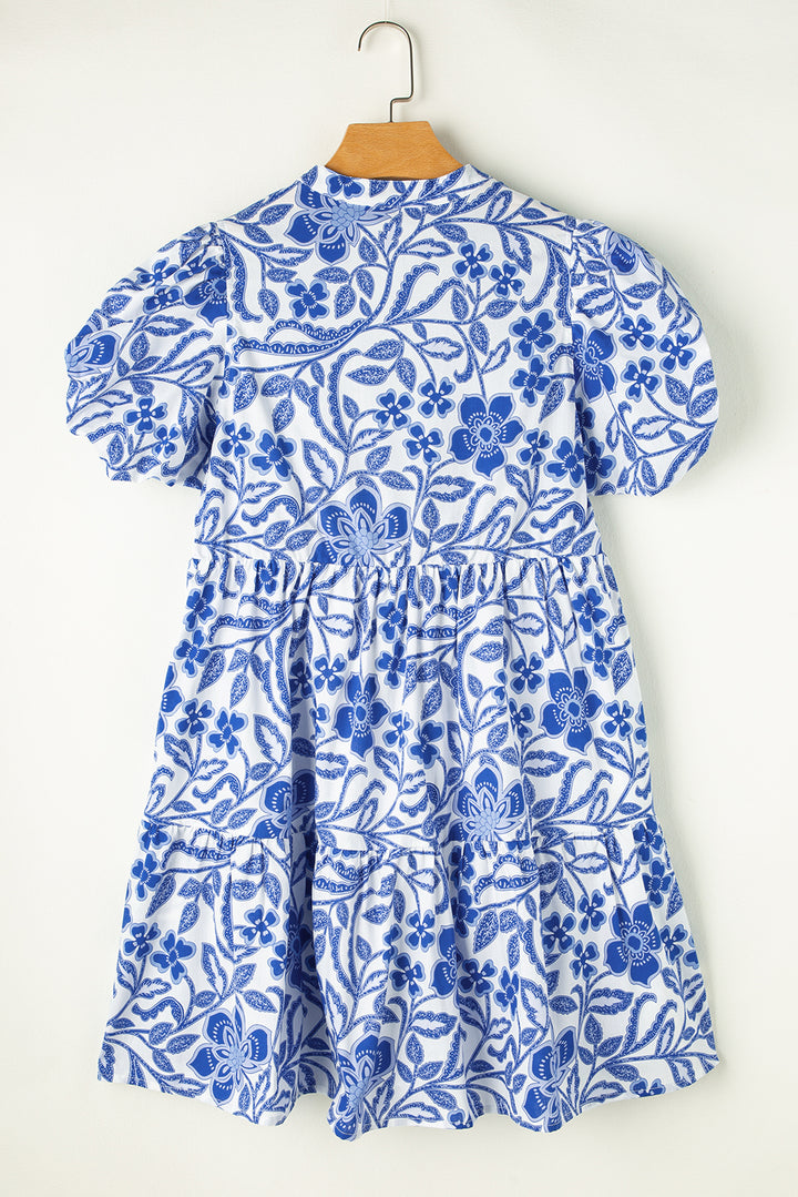 Blue floral dress on a hanger against a white background