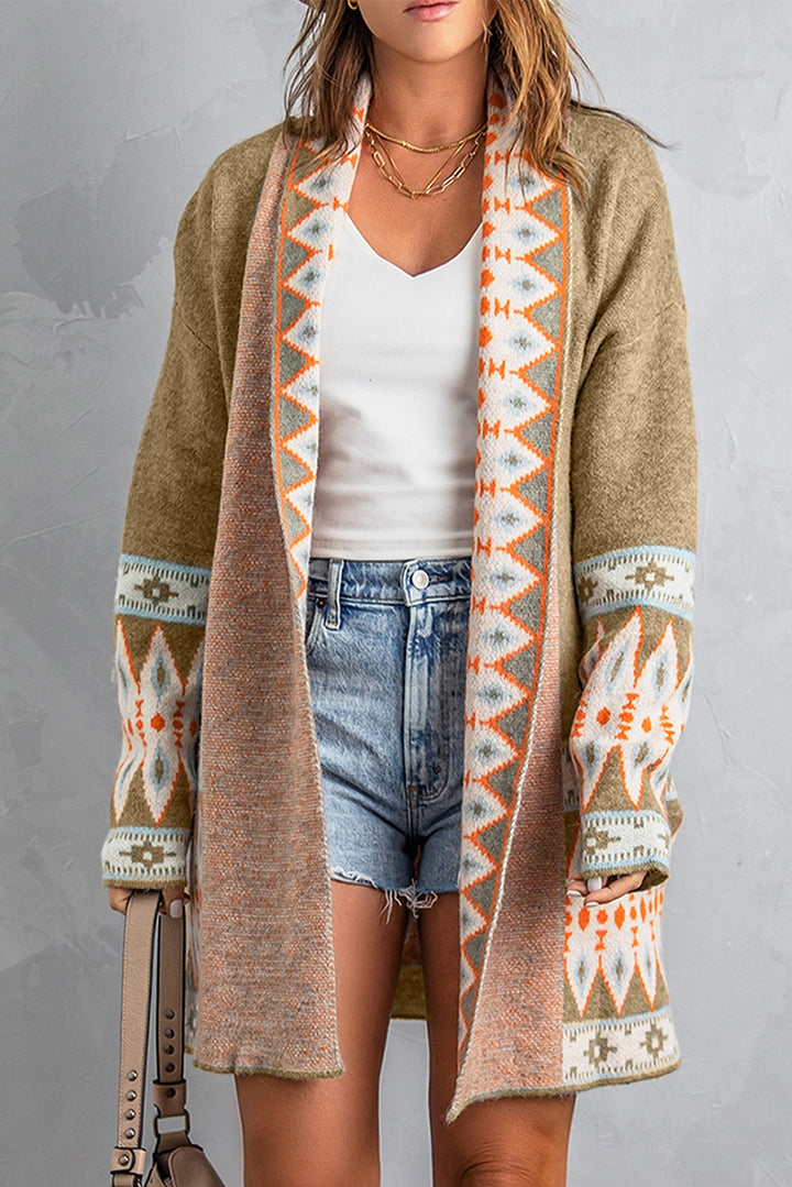 Person wearing a patterned cardigan over a white top and denim shorts on a gray background