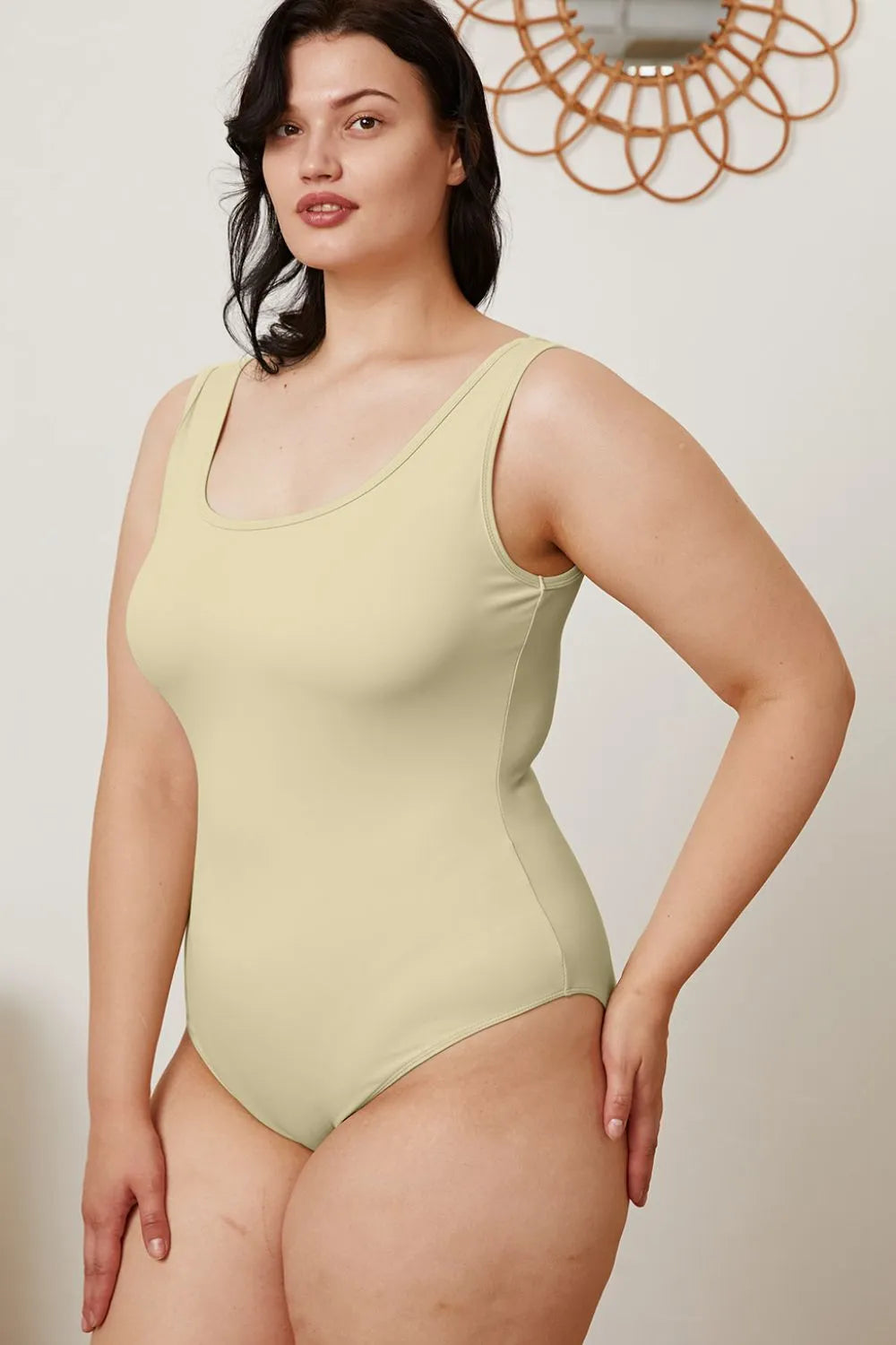 Woman wearing a light green swimsuit against a plain background