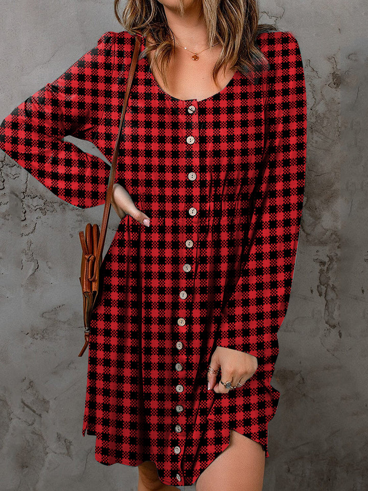 Person wearing a red and black plaid dress with a brown leather bag against a gray background