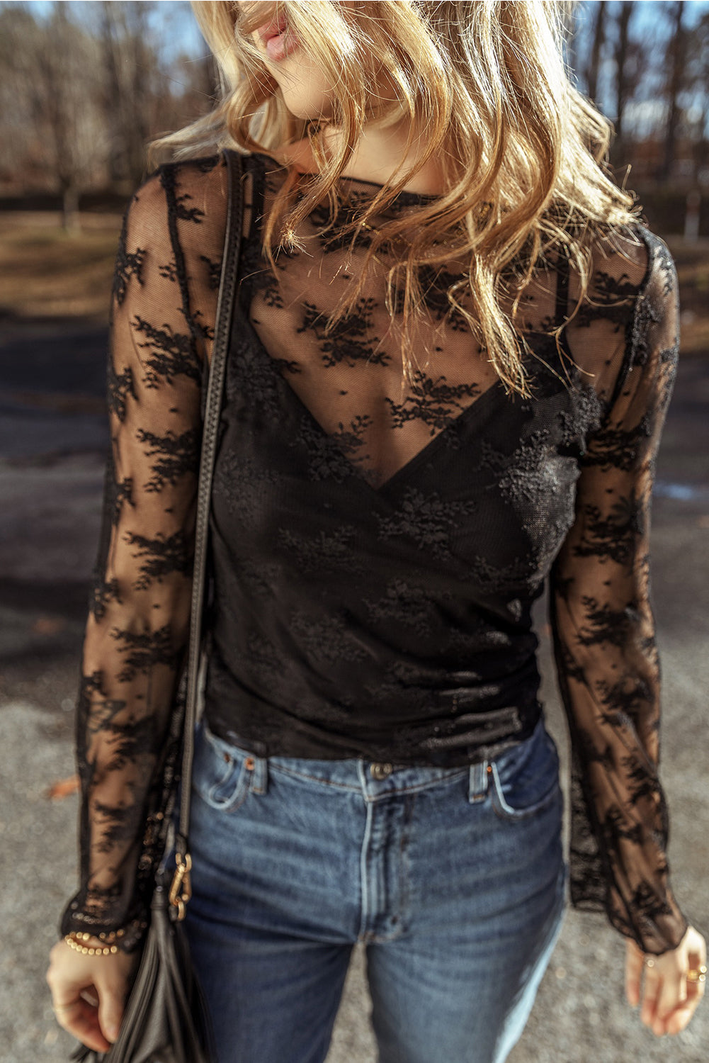 Woman wearing a black lace top and blue jeans outdoors