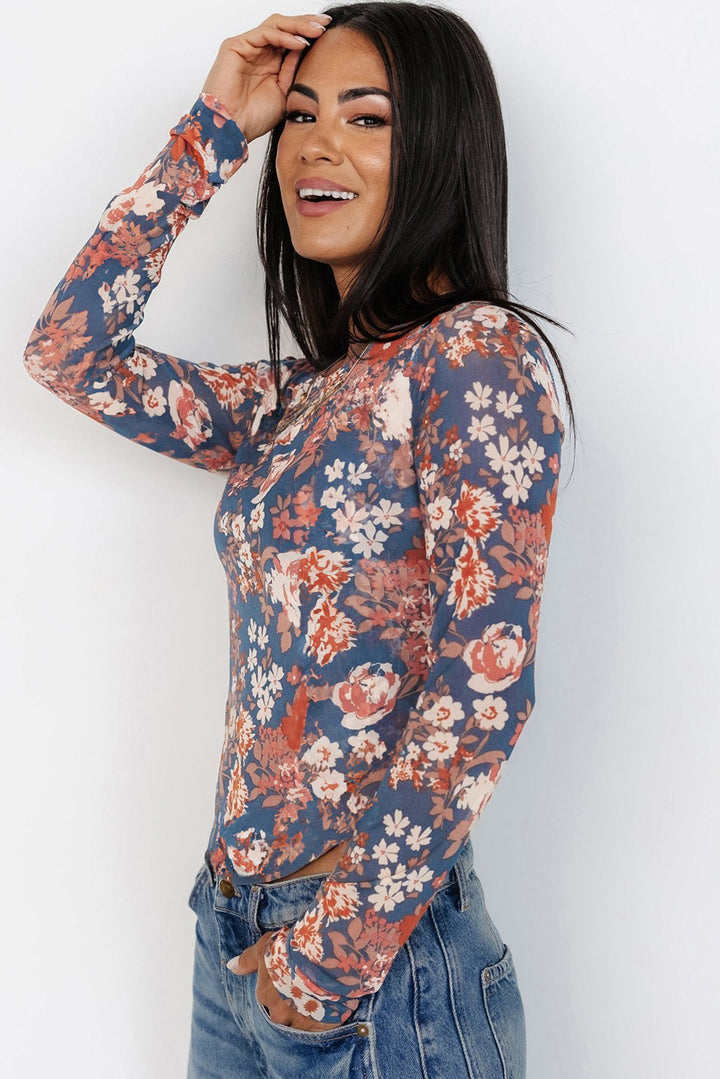 Woman wearing a floral long-sleeve top against a white background