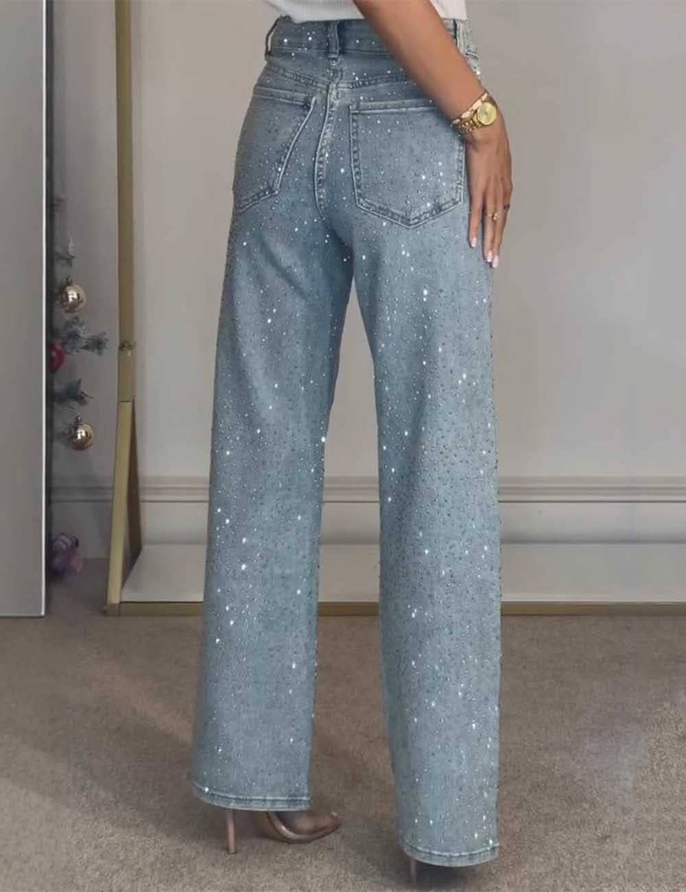 Person wearing sparkly blue jeans in a room with a neutral background