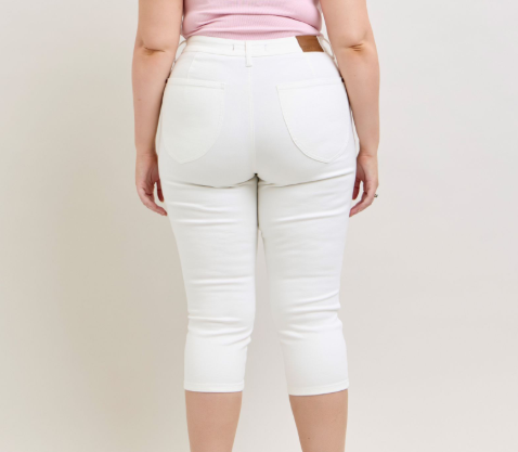 Person wearing white capri pants on a plain background