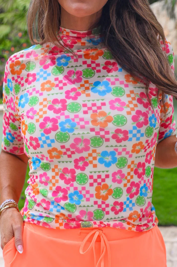 Person wearing a colorful floral patterned shirt with pink pants outdoors.