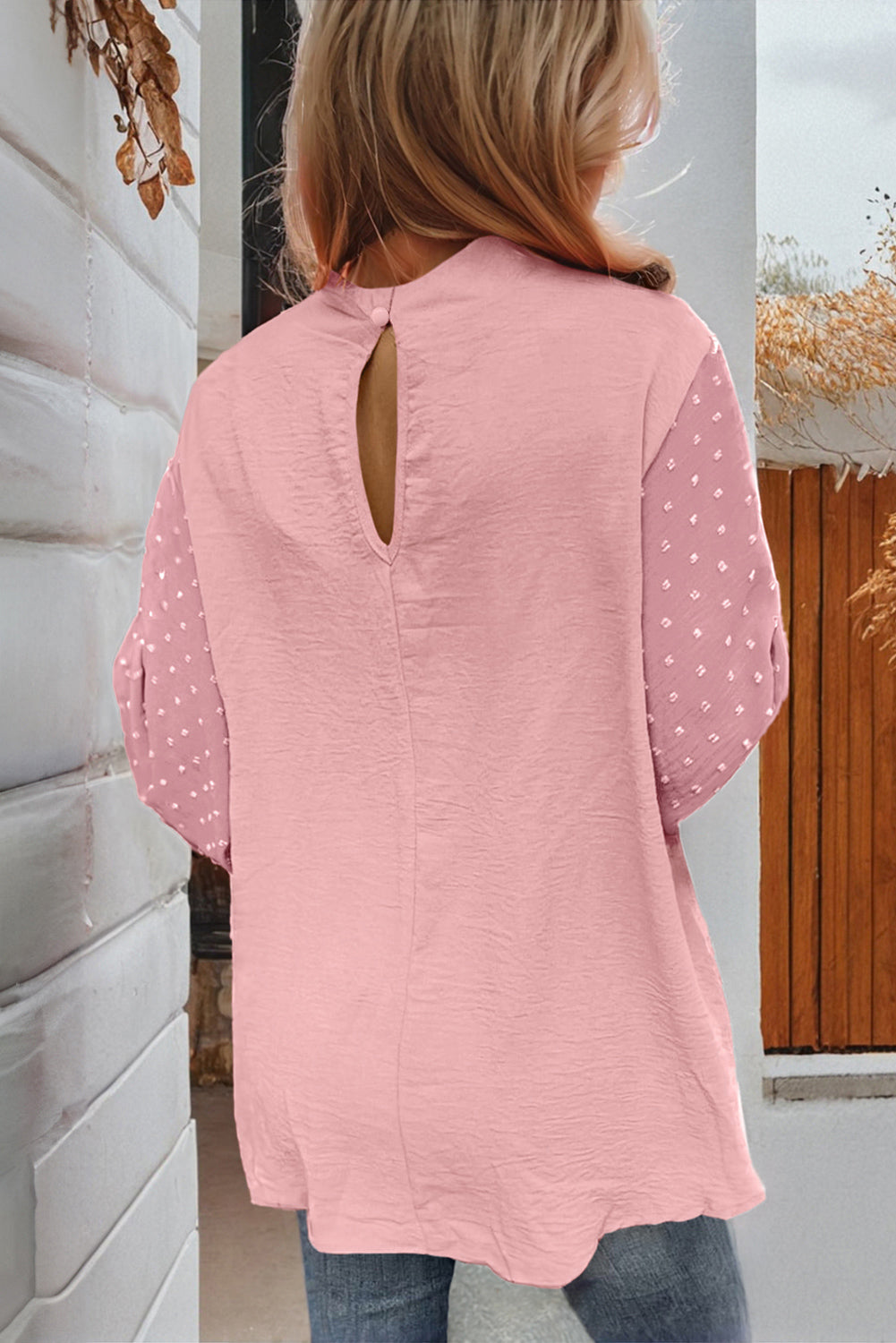 Person wearing a pink blouse with a cut-out back design.