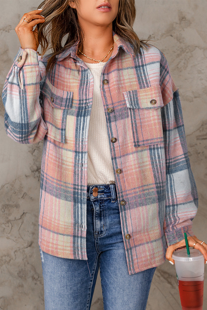 Person wearing a plaid shirt and jeans, holding a drink with a straw.