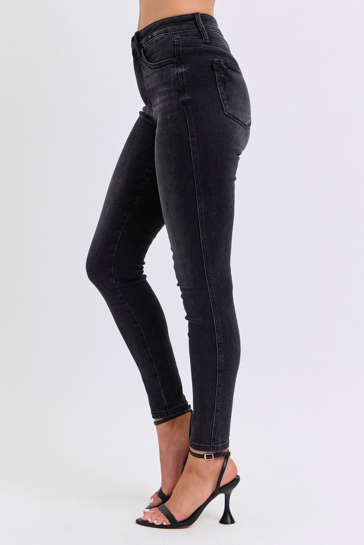 Woman wearing black skinny jeans with white background, side view. Judy Blue Jeans (NP) - Mid Rise Tummy Control Skinny - black | Nikki &amp; Co. Boutique
