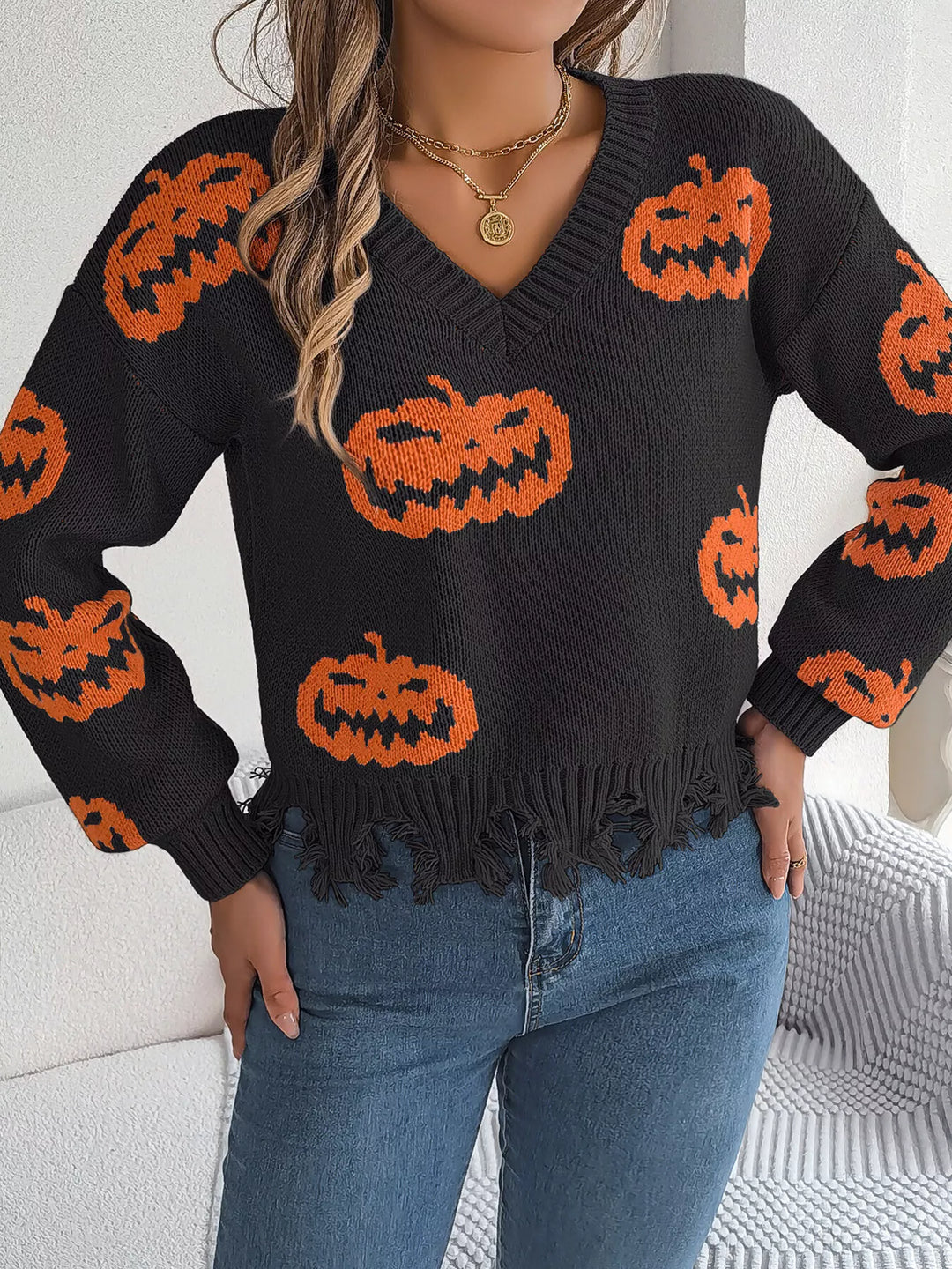 Women wearing black sweater with pumpkins on it while standing with hands on hips