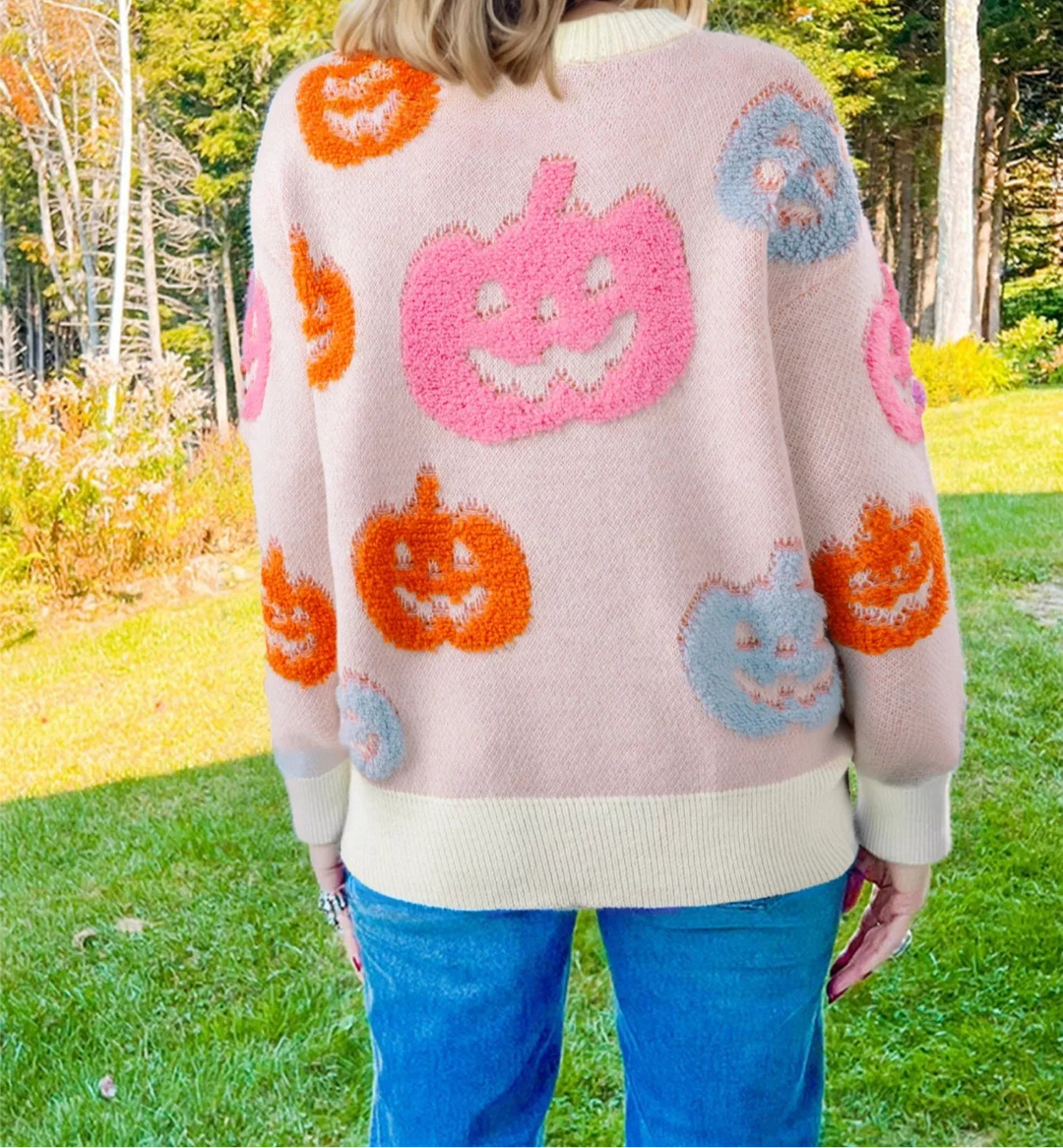 Picture of a women facing the yard wearing a dusty pink sweatshirt with blue, pink. and orange pumpkins on it