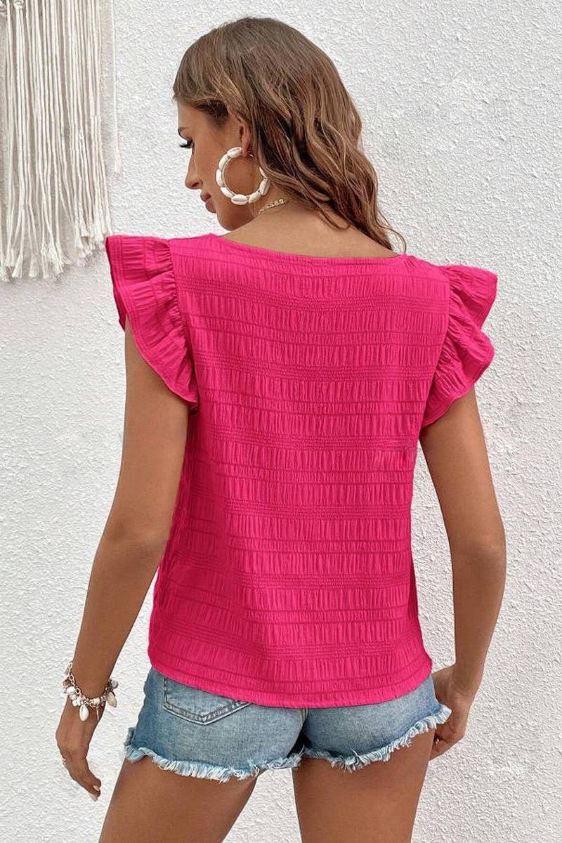 Woman wearing a textured, rose-colored top with ruffled sleeves and square neckline and a pair of jean shorts