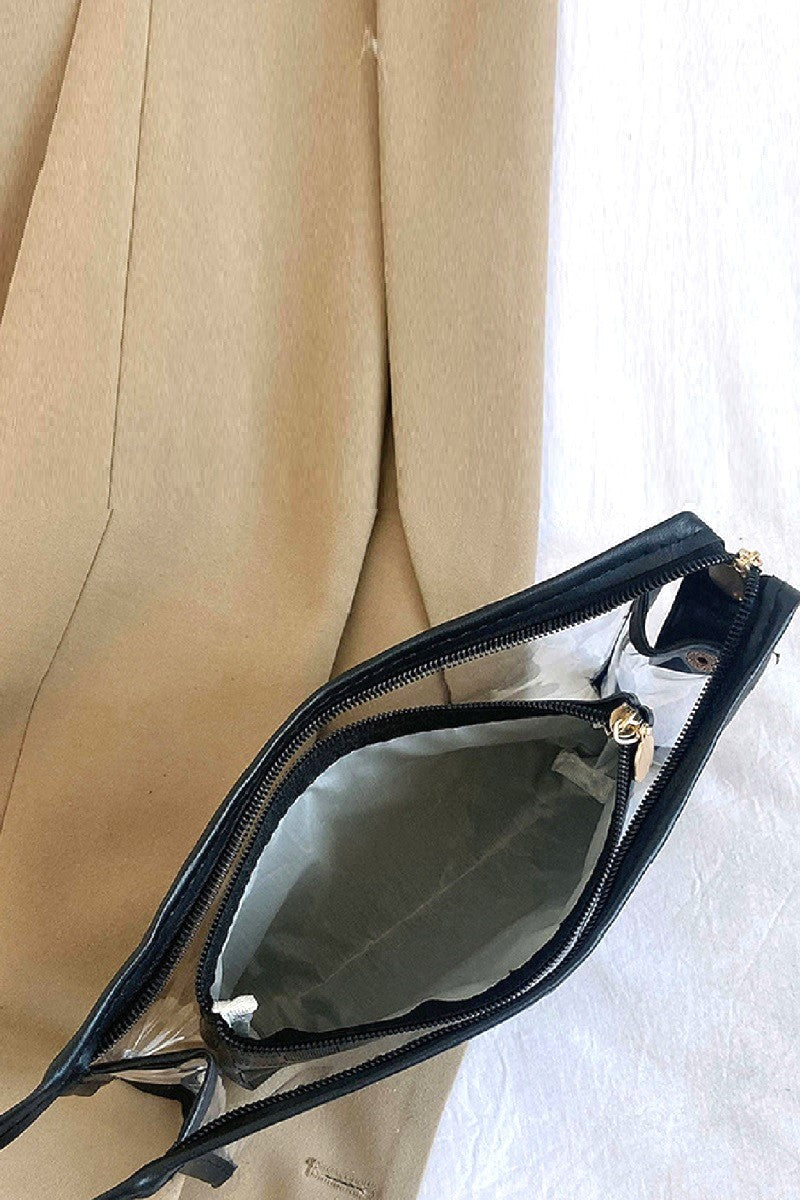 Black handbag with gold zipper pull on a beige fabric background