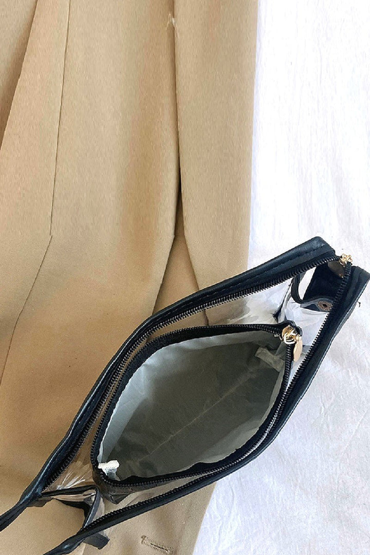 Black handbag with gold zipper pull on a beige fabric background