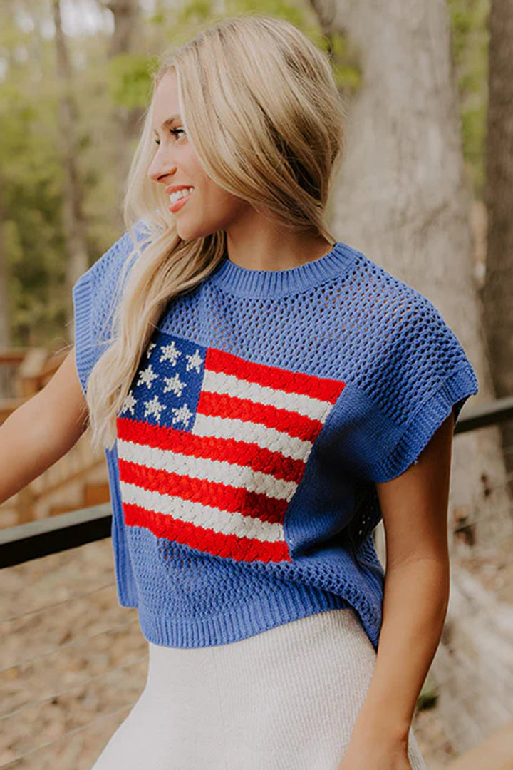 Woman wearing a blue sweater with an American flag design outdoors.