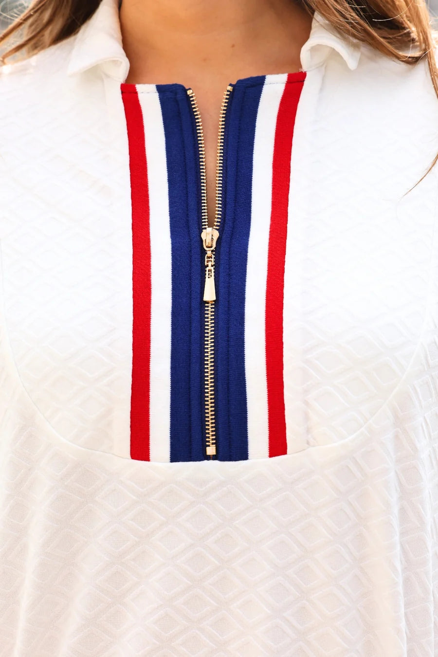 Close-up of a white shirt with a red, white, and blue striped zipper.