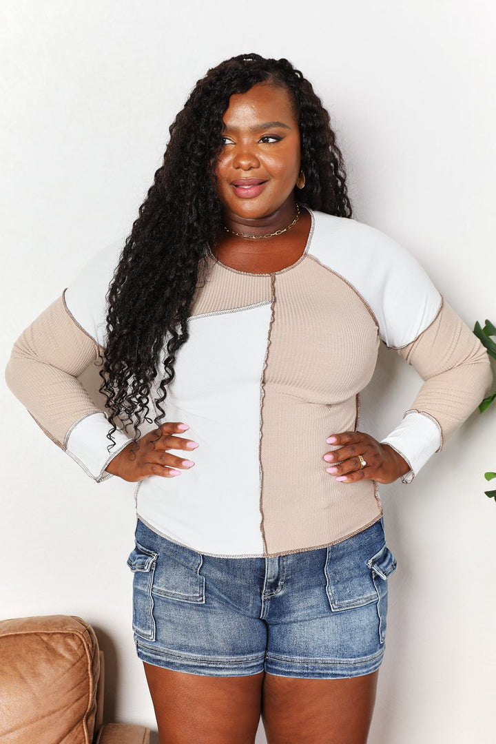 Woman wearing a beige and white sweater with denim shorts against a white background