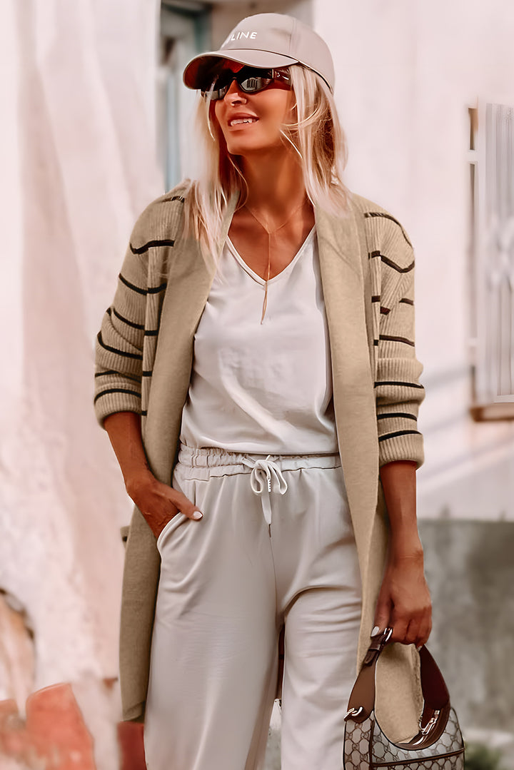 Woman wearing a beige cardigan, white pants, and sunglasses outdoors.