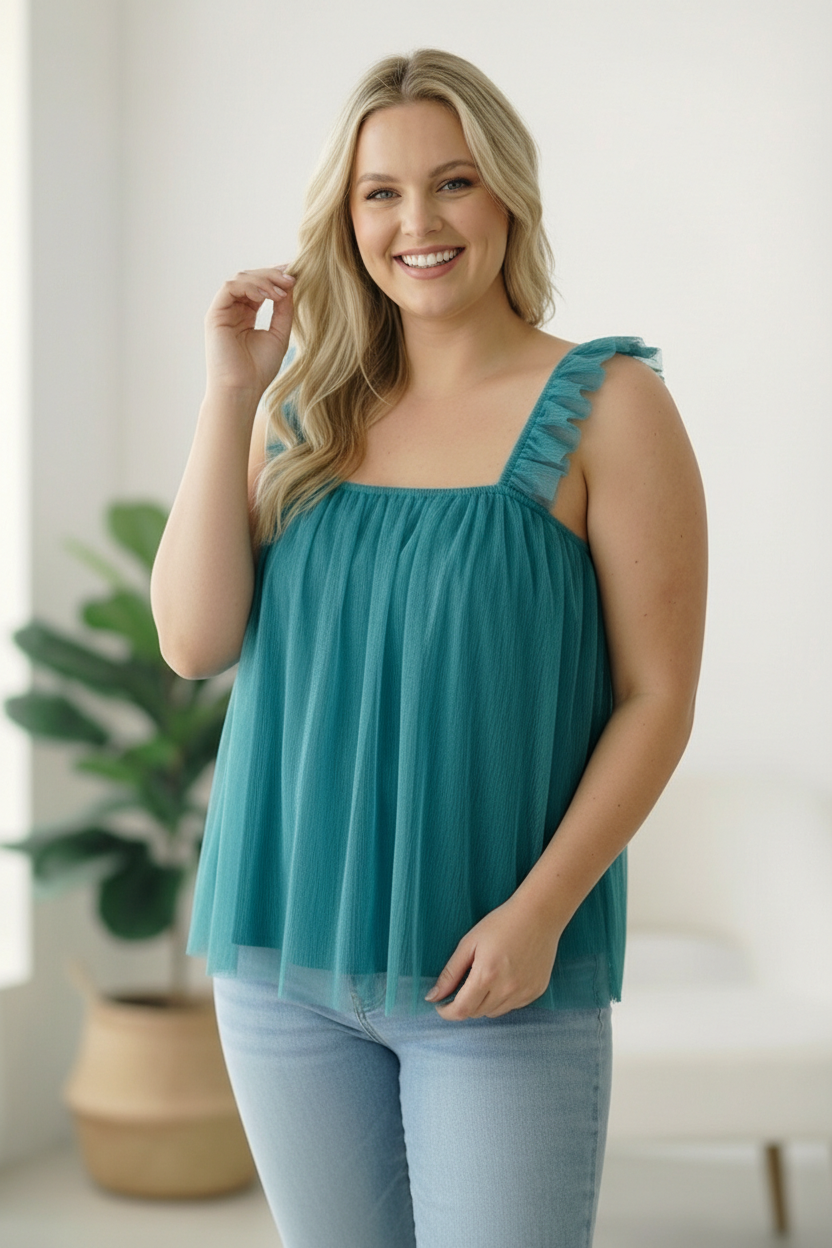 Woman wearing a teal top with ruffled straps in a bright room.
