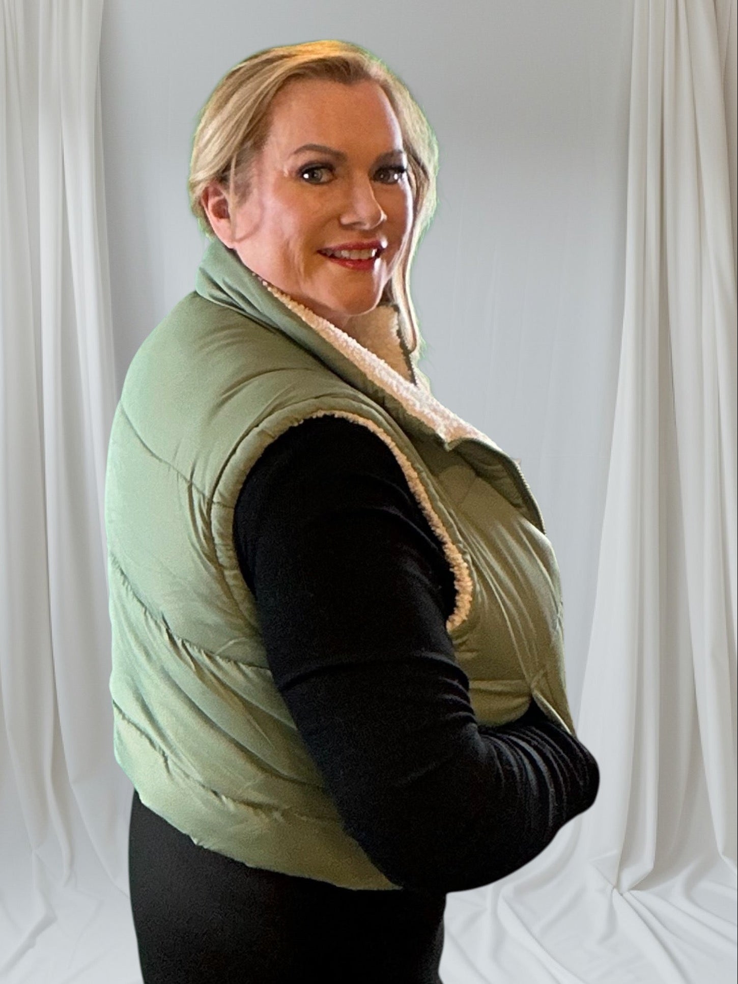 Woman wearing a green puffer vest with a white background