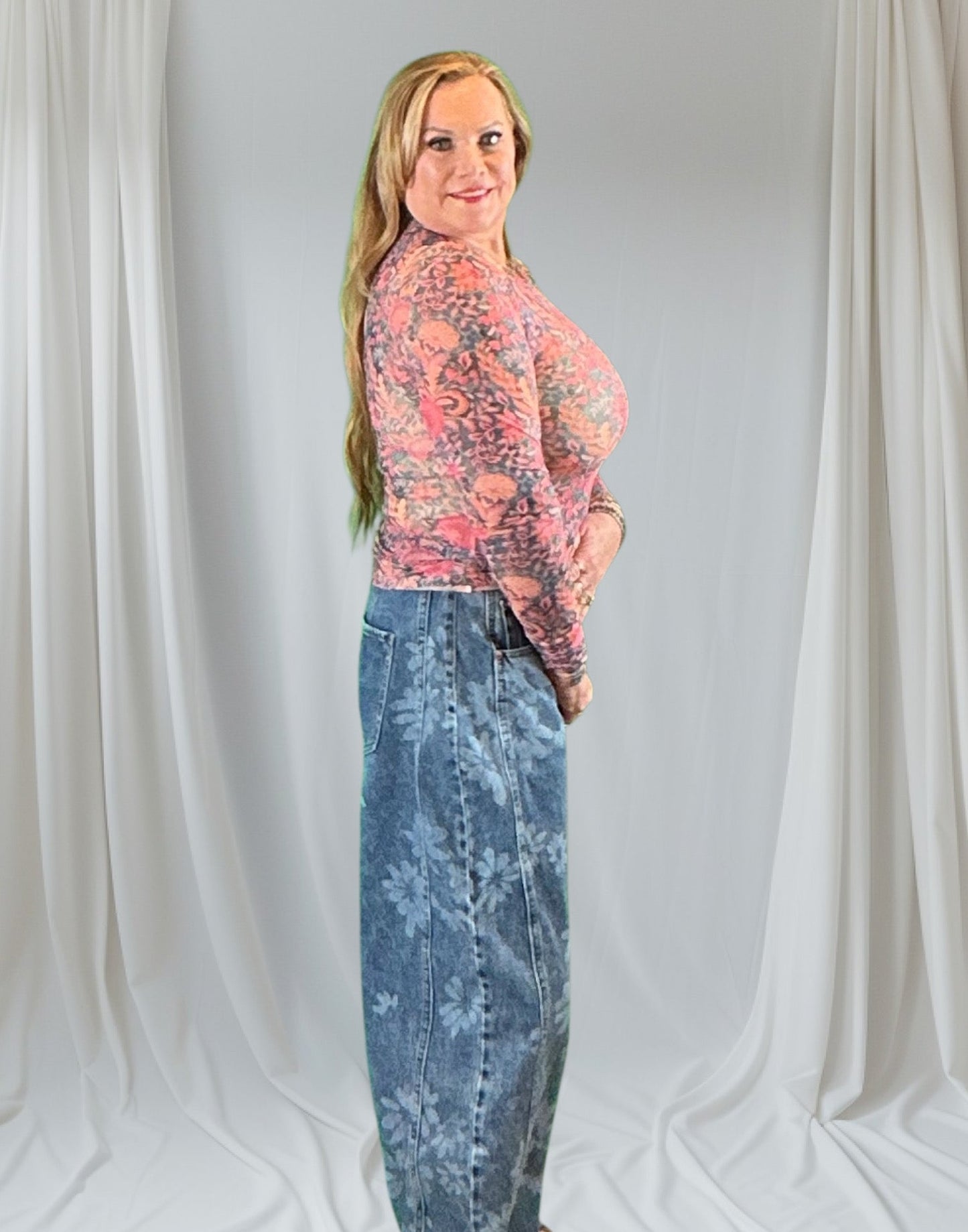 Person wearing a floral top and blue jeans against a plain background