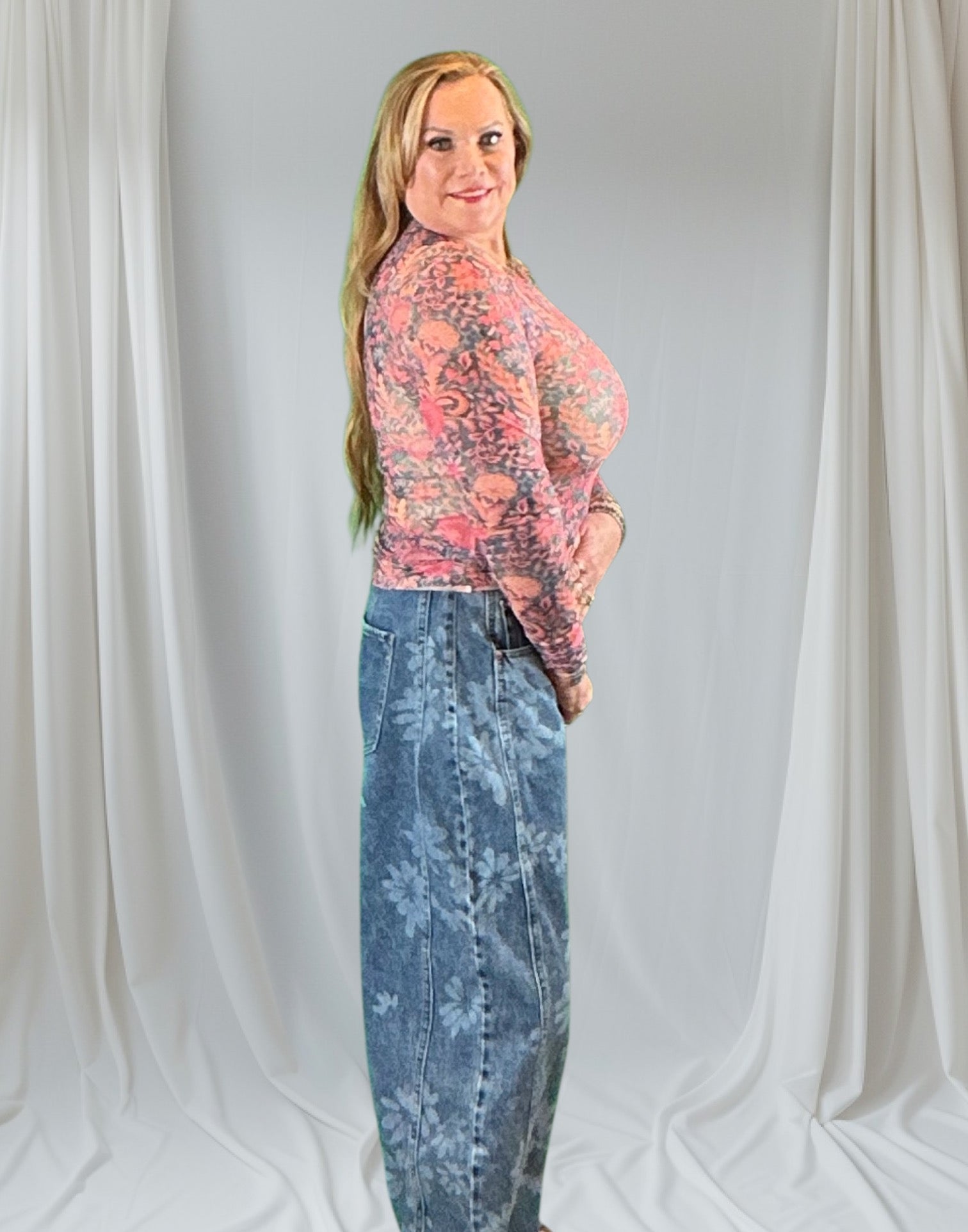 Person wearing a floral top and blue jeans against a plain background