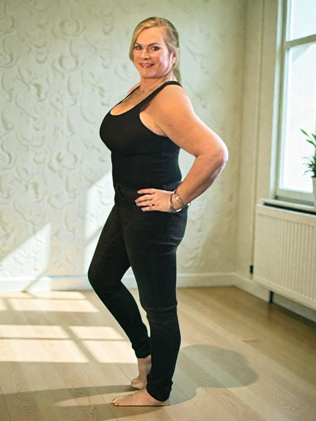 Woman wearing black skinny jeans and tank top against white wall. Judy Blue Jeans (NP) - Mid Rise Tummy Control Skinny - black | Nikki &amp; Co. Boutique