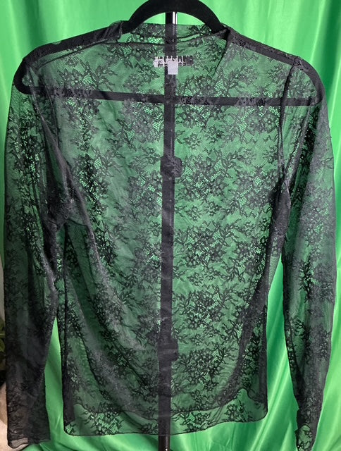 Green lace top on a hanger against a green background