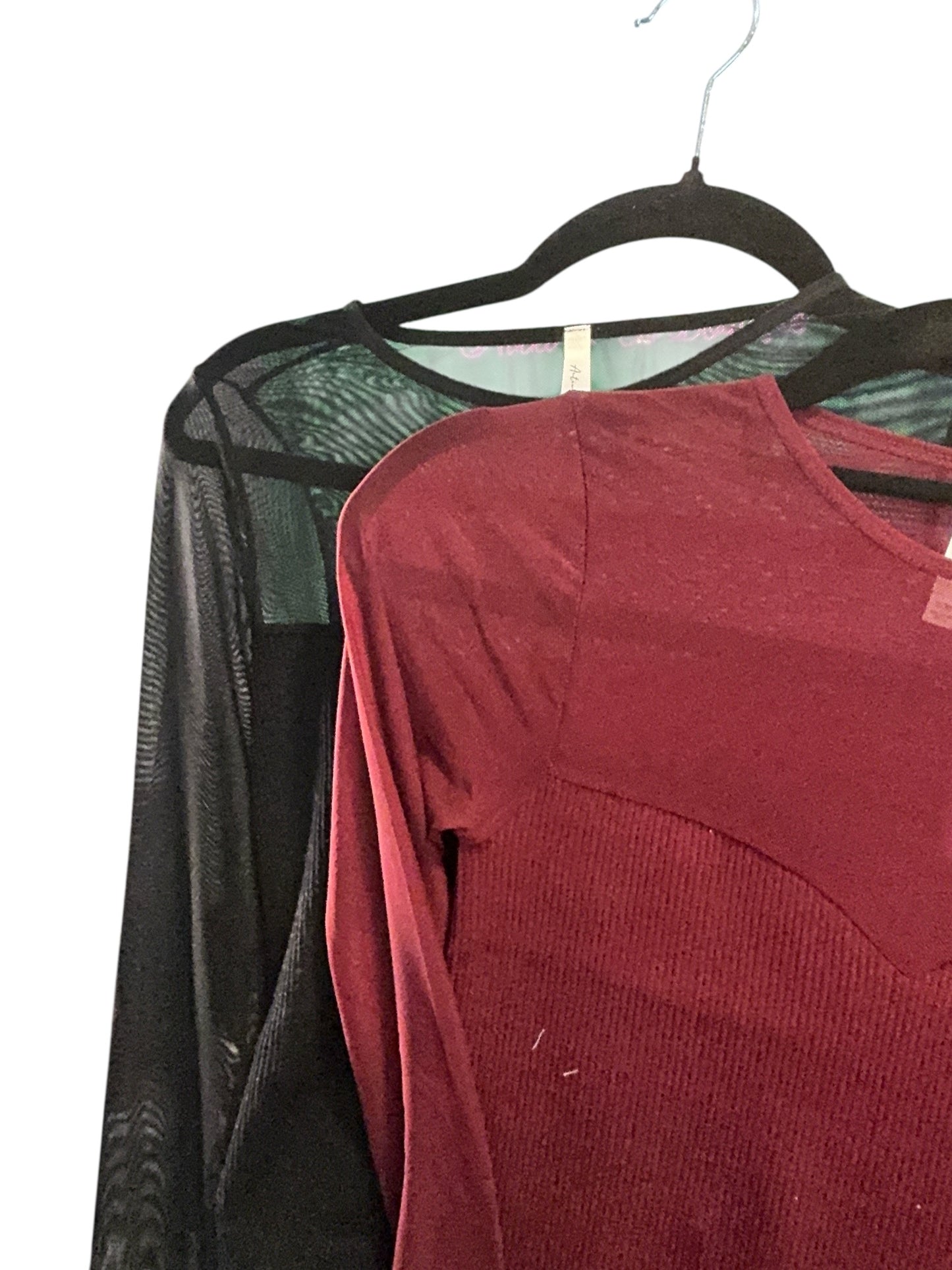 Red shirt and black sheer fabric on a hanger against a white background