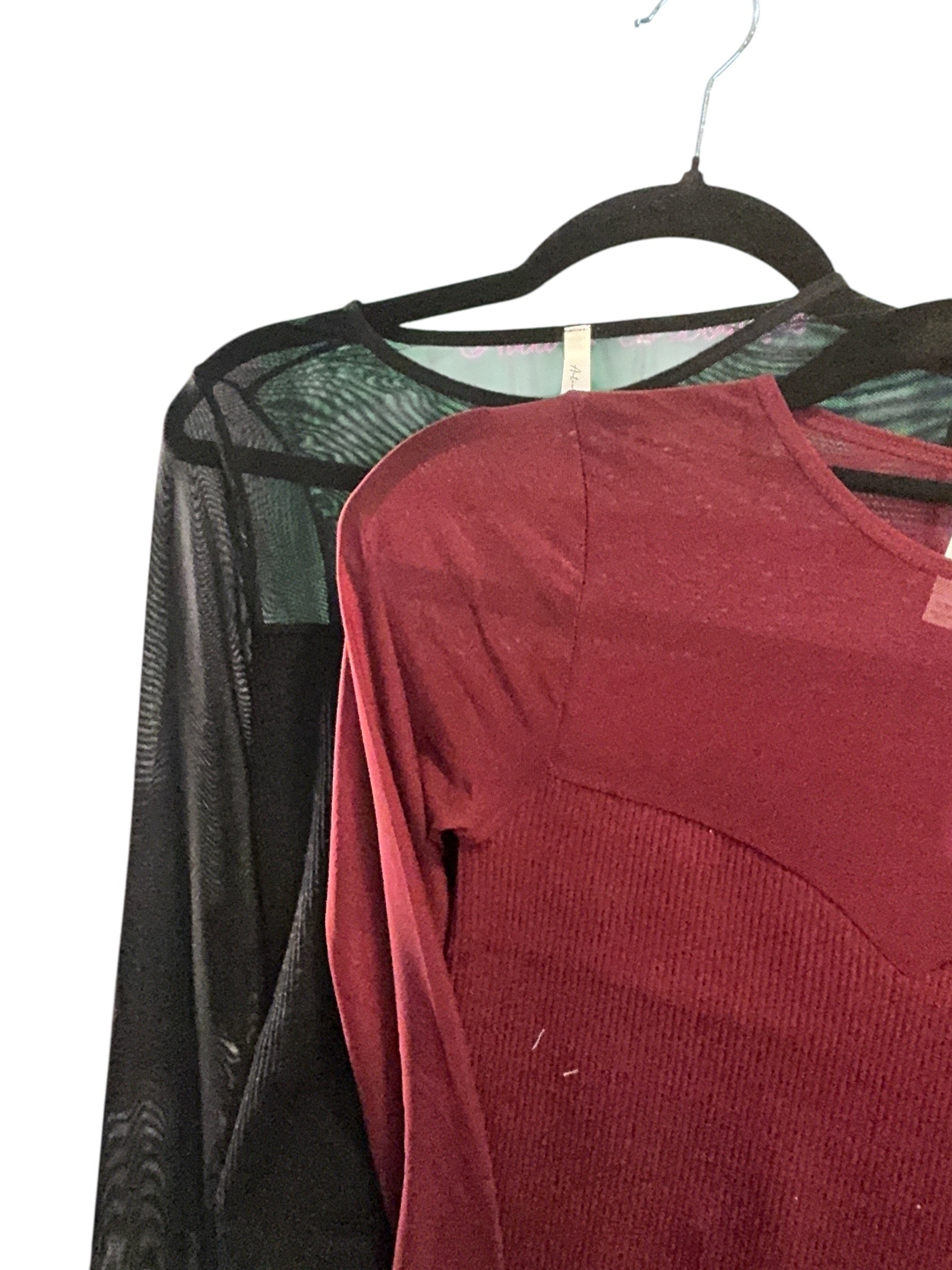 Red shirt and black sheer fabric on a hanger against a white background