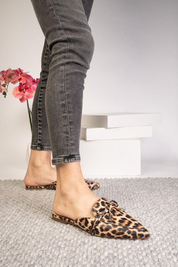 Person wearing leopard print flats with gray jeans on a light background