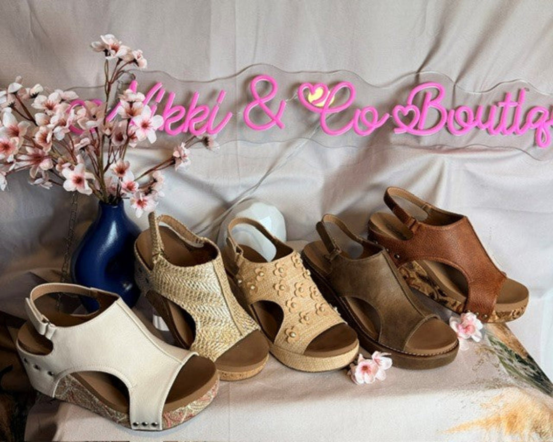 Set of women's sandals on a white surface with decorative flowers and 'Bekel & Co Boutique' sign.