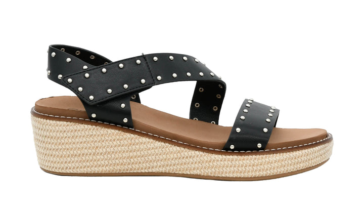Black wedge sandal with studded details on a white background