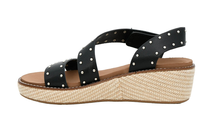 Black wedge sandal with metal stud details on a white background
