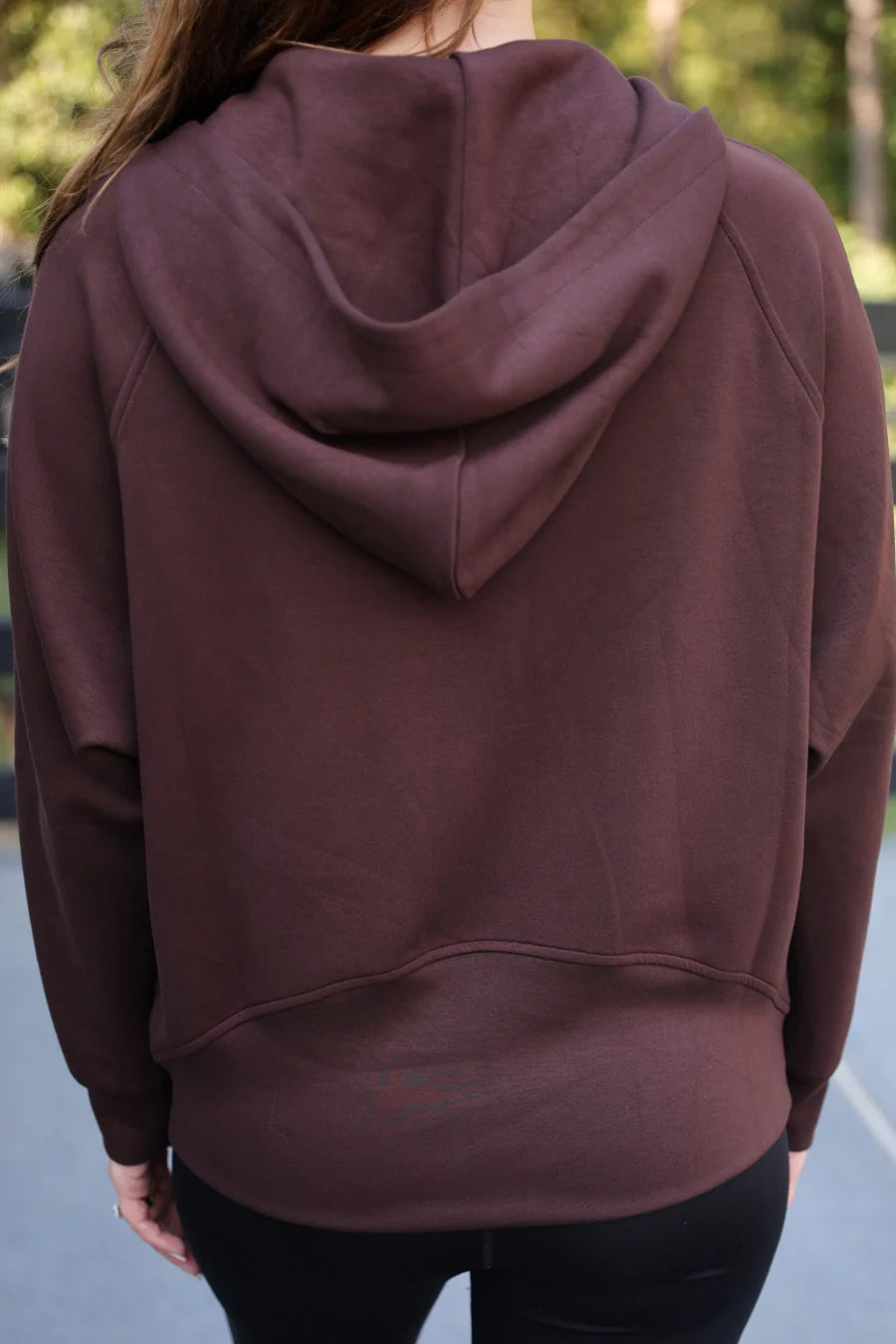 Person wearing a chocolate hoodie with a blurred outdoor background