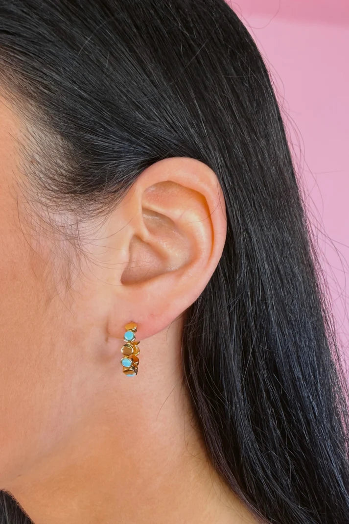 Woman wearing a colorful, small hoop earring.