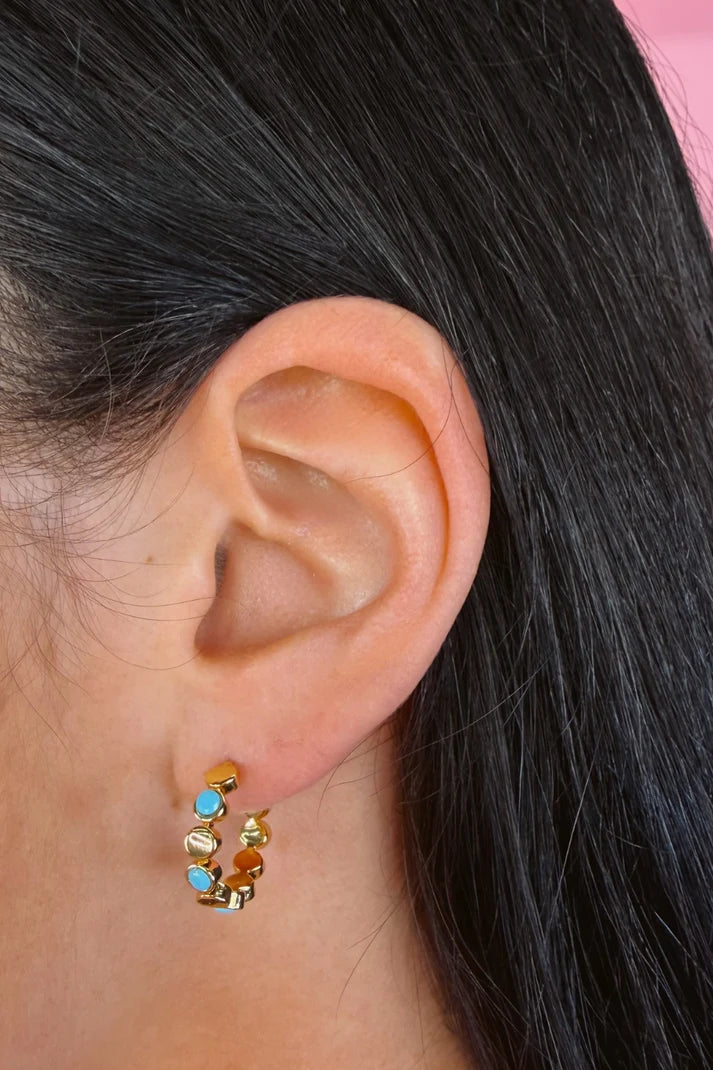 Woman wearing a colorful, small hoop earring.