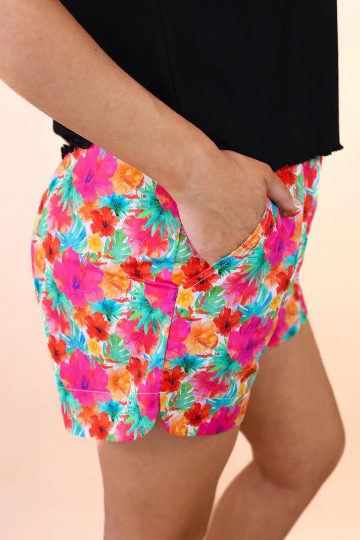 Colorful floral shorts worn by a person on a beige background
