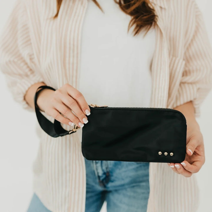 Woman holding a black wristlet wallet