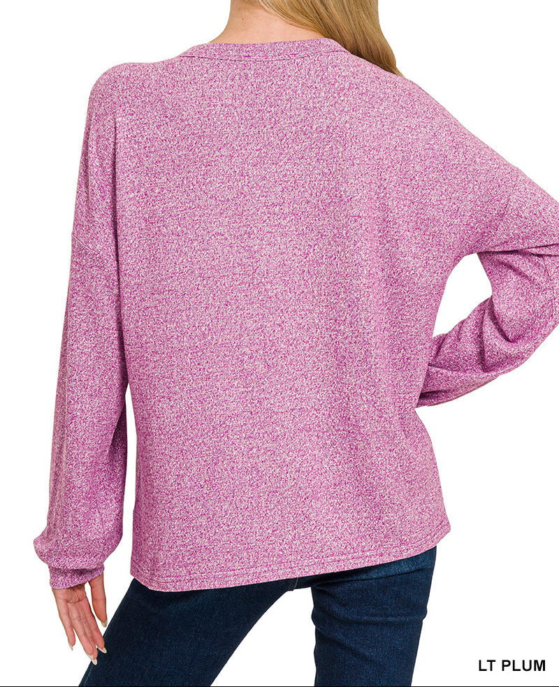 Woman wearing light plum top facing the wall