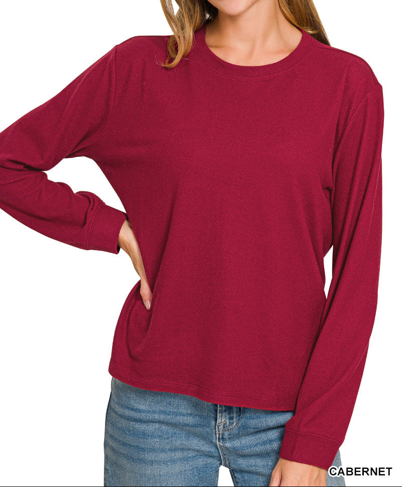Woman wearing cabernet colored top and jeans
