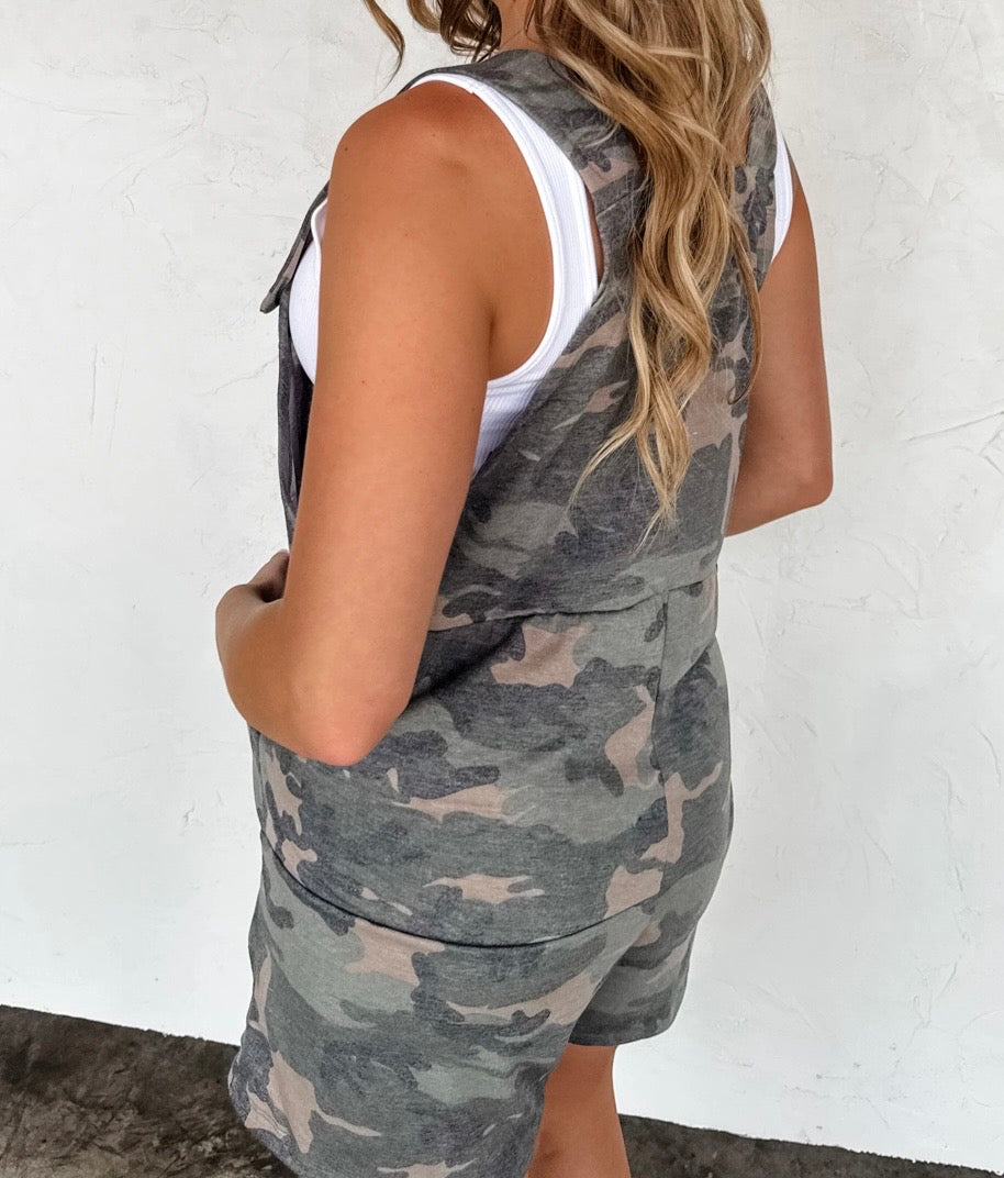 Person wearing a camouflage tank top and shorts set with a white background