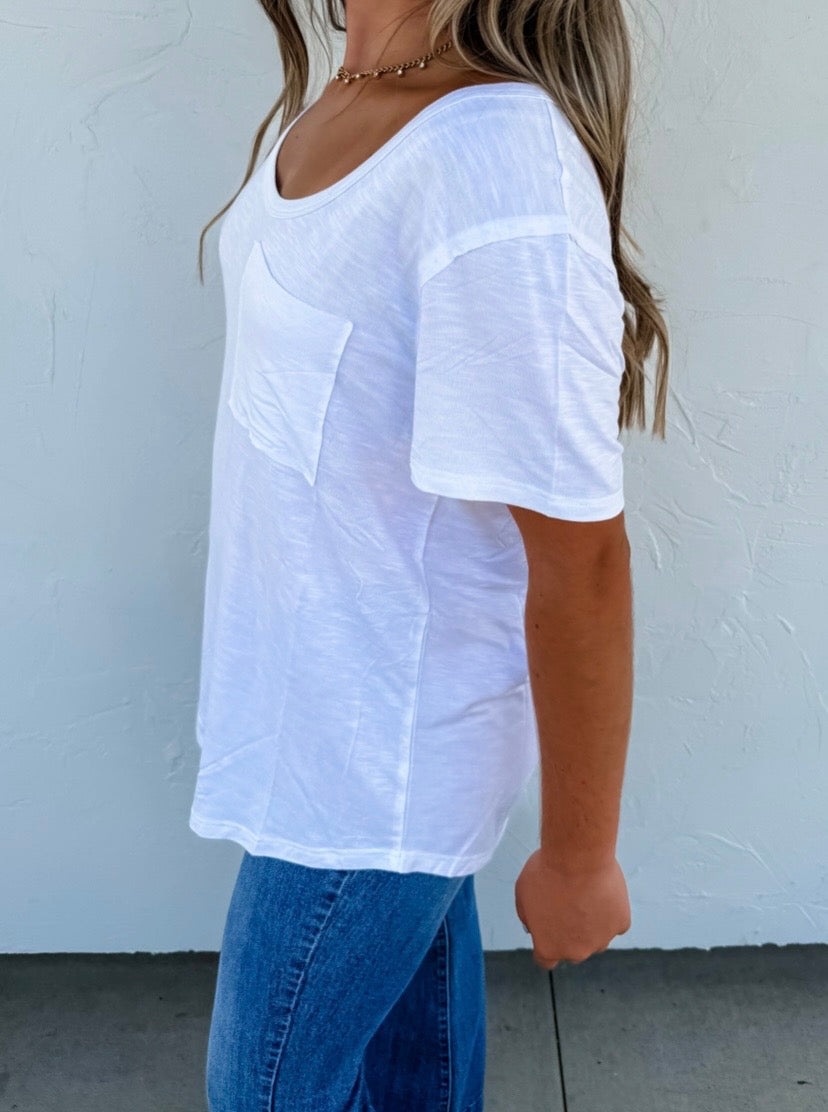 Person wearing a white oversized t-shirt and blue jeans against a plain background