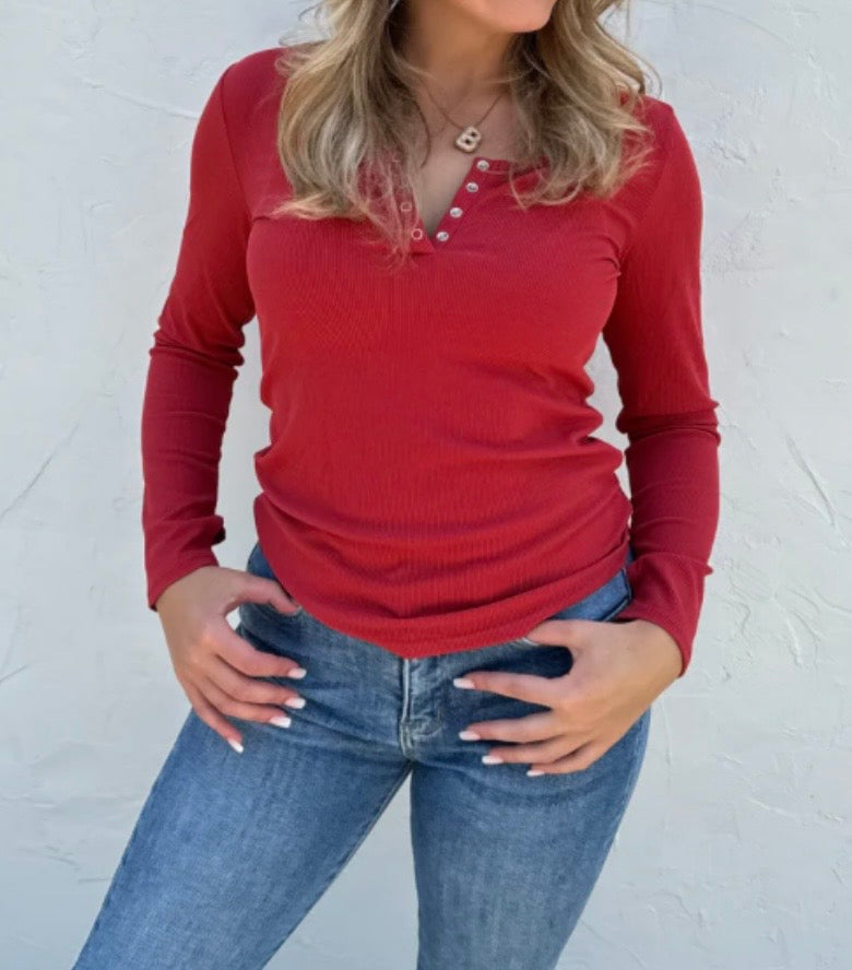 Person wearing a red long-sleeve top and blue jeans against a white background