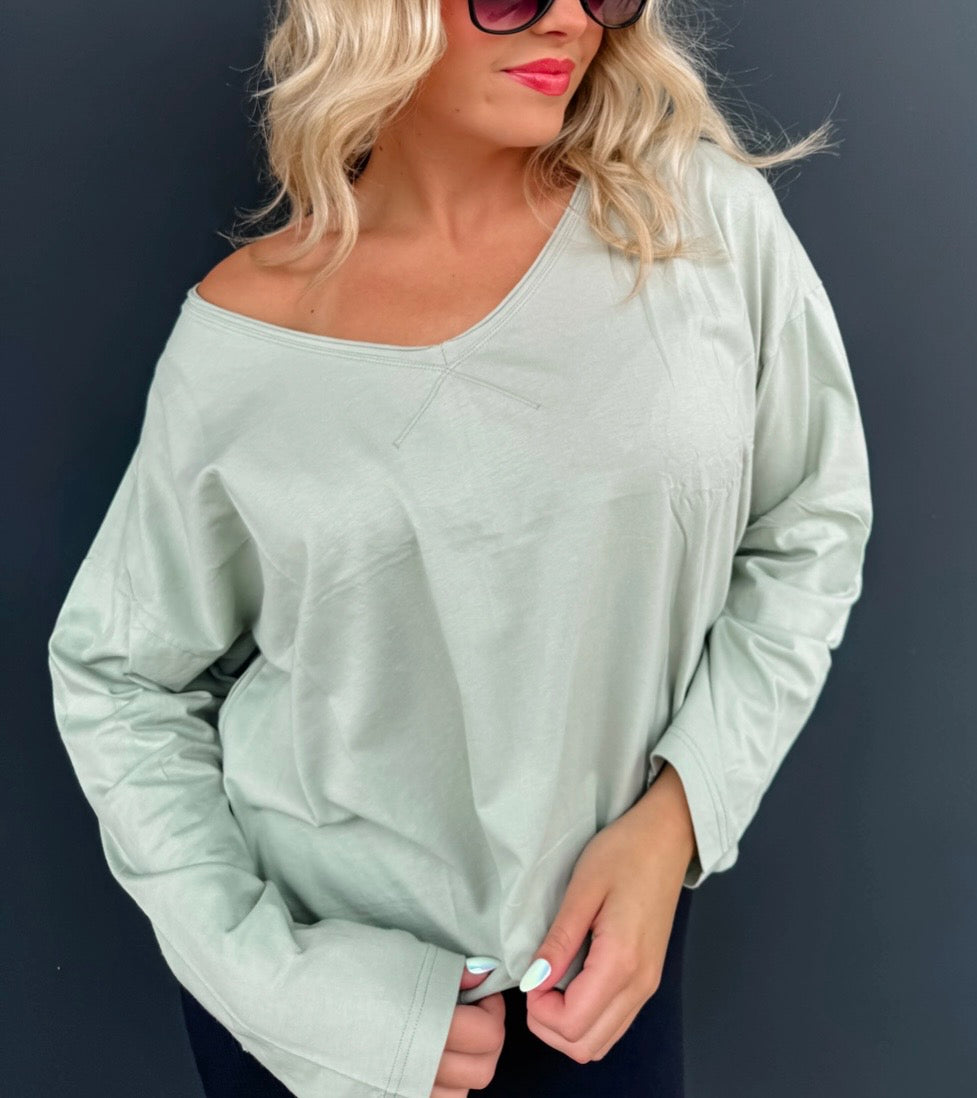 Woman wearing a light green oversized sweater against a dark background