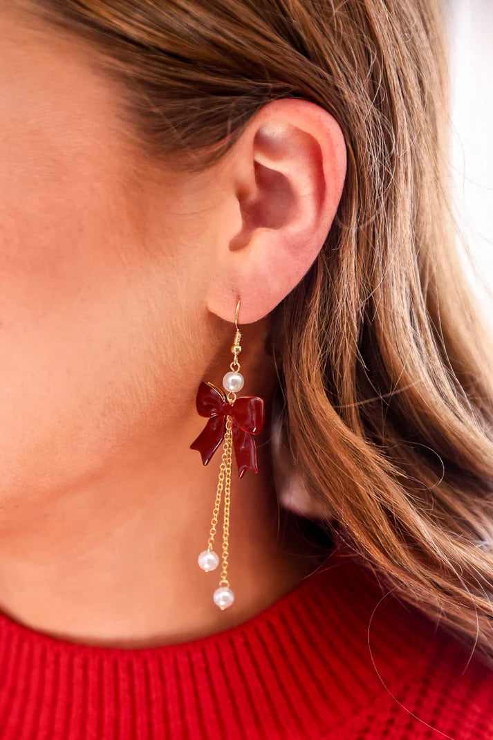 Woman wearing a red bow earring.