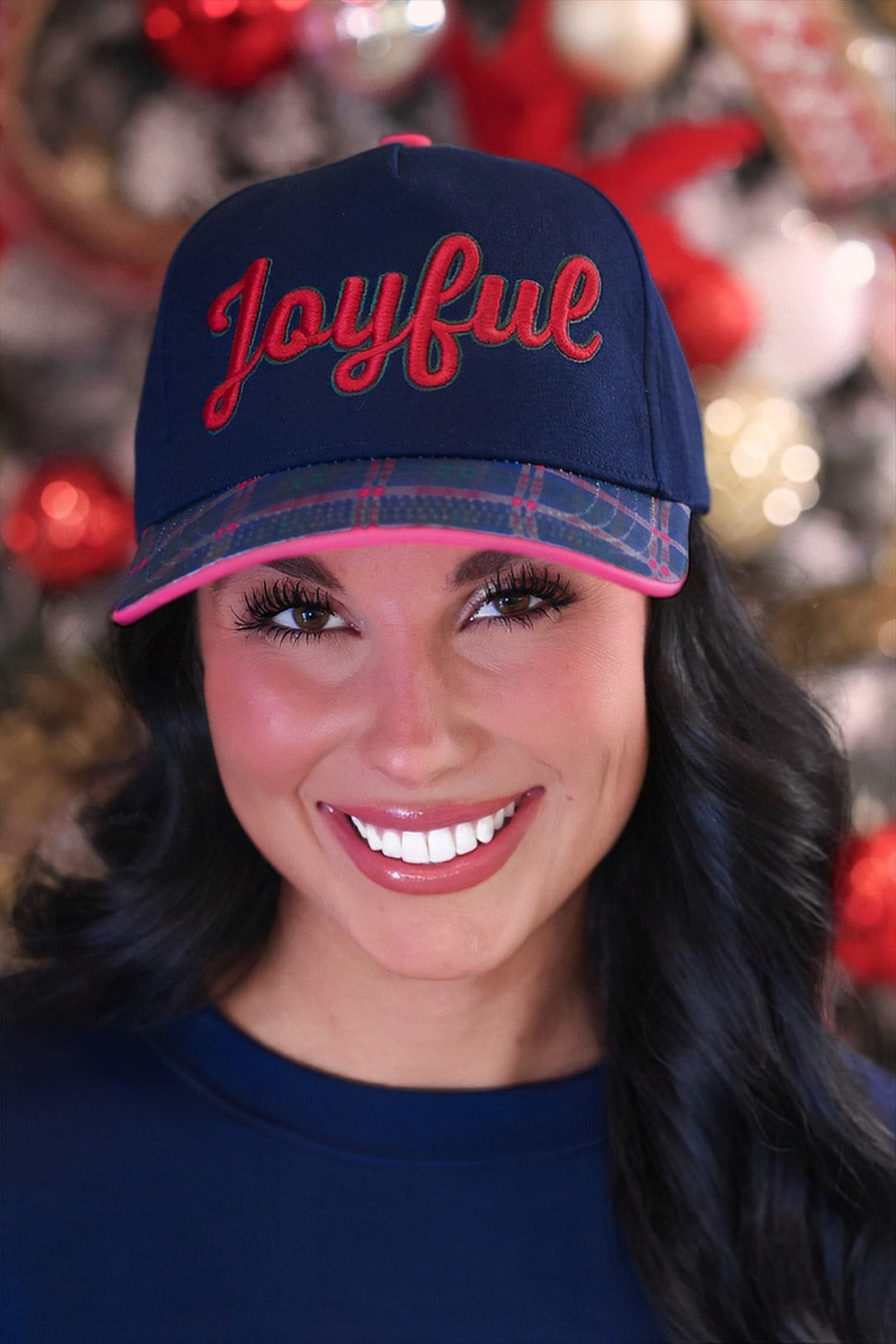 A smiling woman wearing a navy blue baseball cap with &