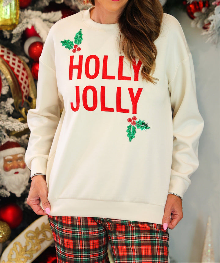 A woman wearing a cream-colored crewneck sweatshirt with &
