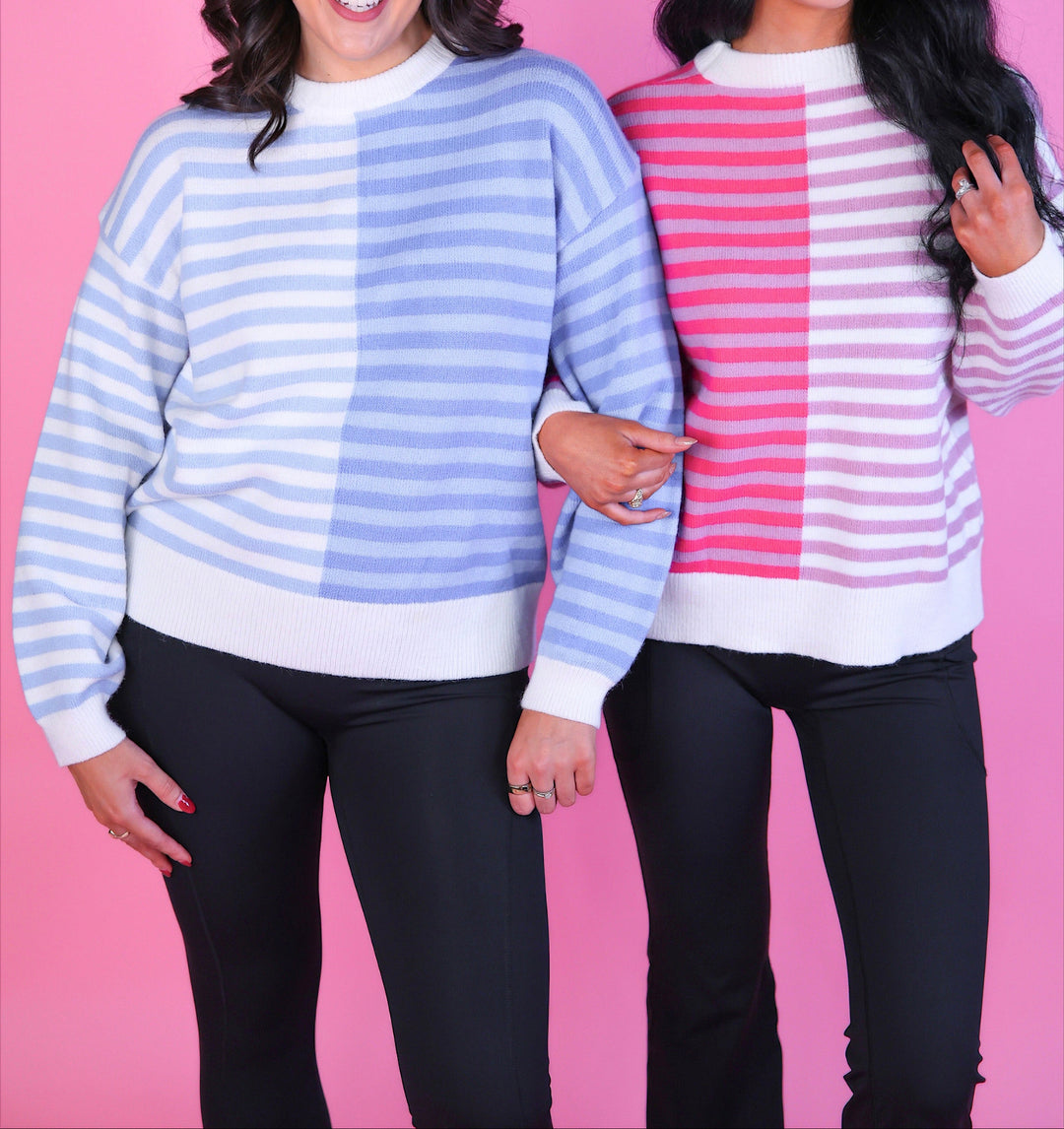 Two wome wearing a pink and white or blue and white striped sweater with long sleeves and black pants.