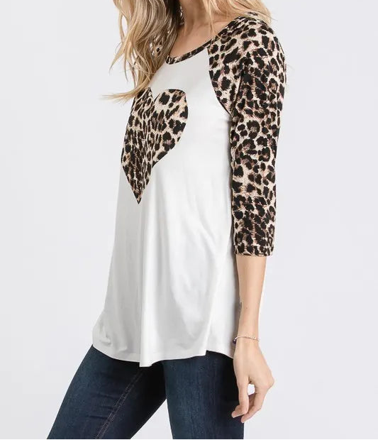 Woman wearing a white top with leopard print sleeves on a plain background